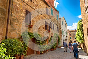 Pienza, Italy Ã¢â¬â May 27, 2017: Beautiful narrow street with sunlight and flowers in the village of Pienza, Italy